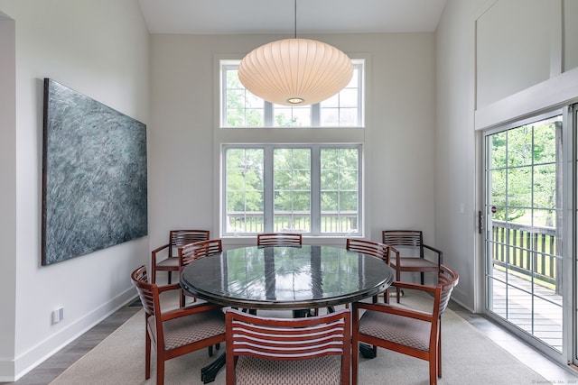 dining space with high vaulted ceiling, wood-type flooring, and plenty of natural light