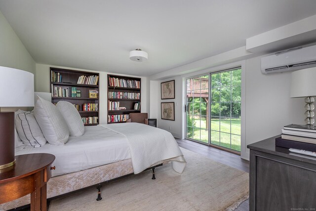 bedroom with an AC wall unit, light hardwood / wood-style floors, access to outside, and multiple windows