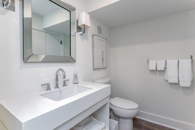 bathroom with visible vents, toilet, wood finished floors, baseboards, and vanity