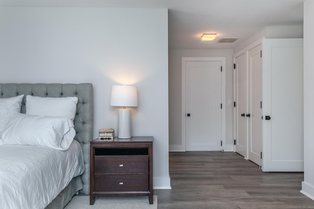 bedroom featuring visible vents, baseboards, and wood finished floors