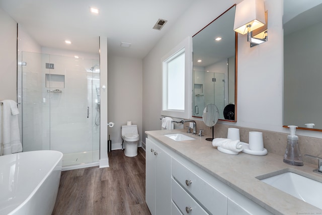 full bathroom with double sink vanity, toilet, hardwood / wood-style floors, and separate shower and tub