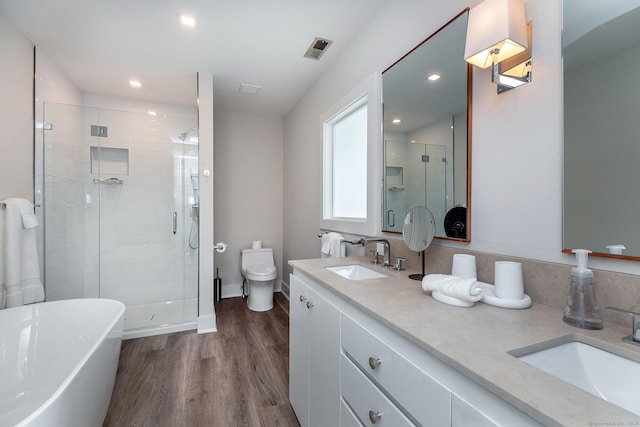 bathroom featuring a shower stall, wood finished floors, toilet, and a sink