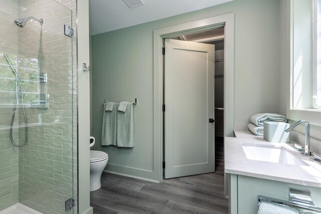 bathroom with wood-type flooring, vanity, walk in shower, and toilet