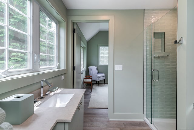 bathroom with vaulted ceiling, walk in shower, vanity, and wood-type flooring