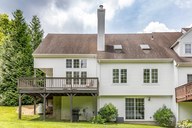 rear view of house featuring a wooden deck and a lawn