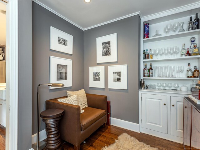 bar featuring a bar, baseboards, dark wood-type flooring, and crown molding