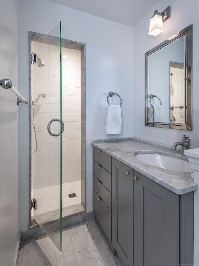 full bathroom with marble finish floor, a shower stall, and vanity