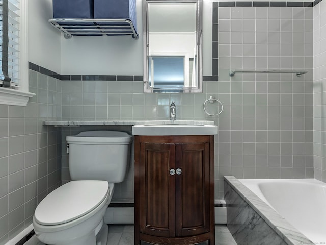 bathroom with toilet, a tub to relax in, vanity, and tile walls