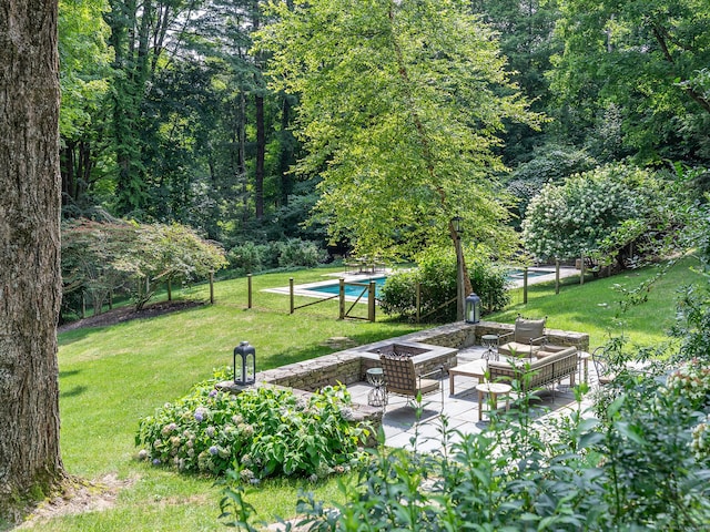 view of community with a yard, a fire pit, a pool, and a patio