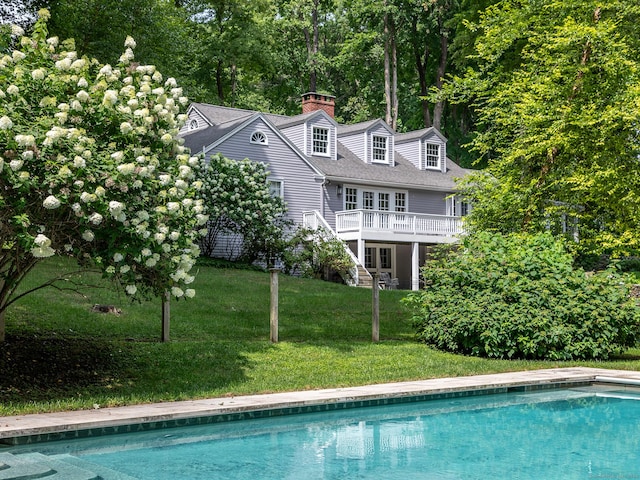 exterior space featuring stairs, a yard, a chimney, and a wooden deck