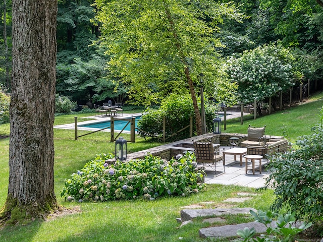 view of property's community with a lawn, a swimming pool, and a patio