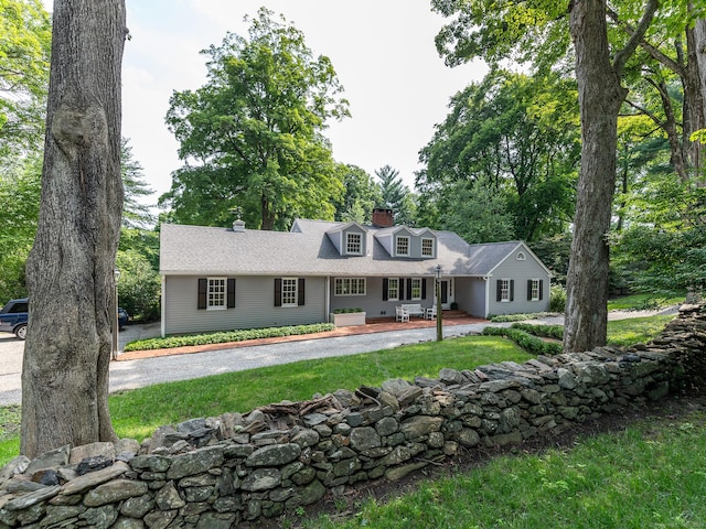 cape cod-style house with a chimney and a front lawn