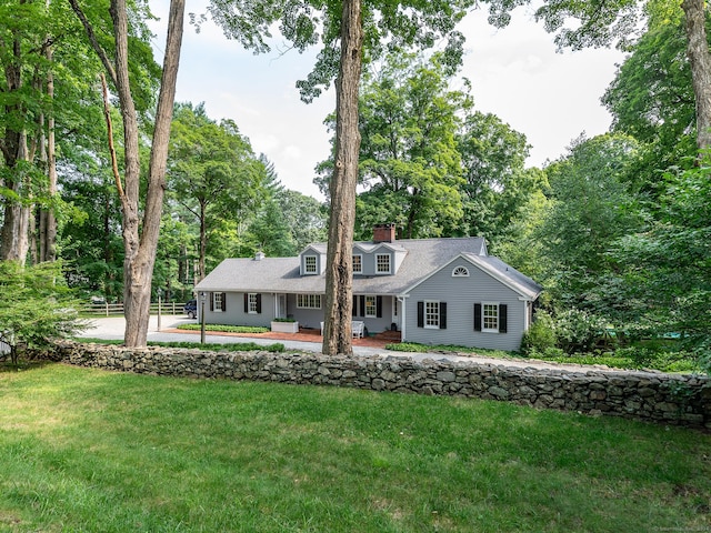 view of front facade with fence, a chimney, and a front lawn