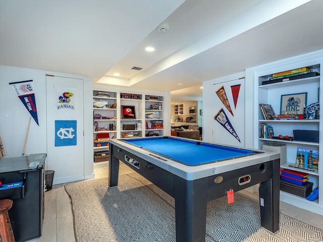 recreation room with visible vents, a raised ceiling, built in features, light wood-style flooring, and recessed lighting