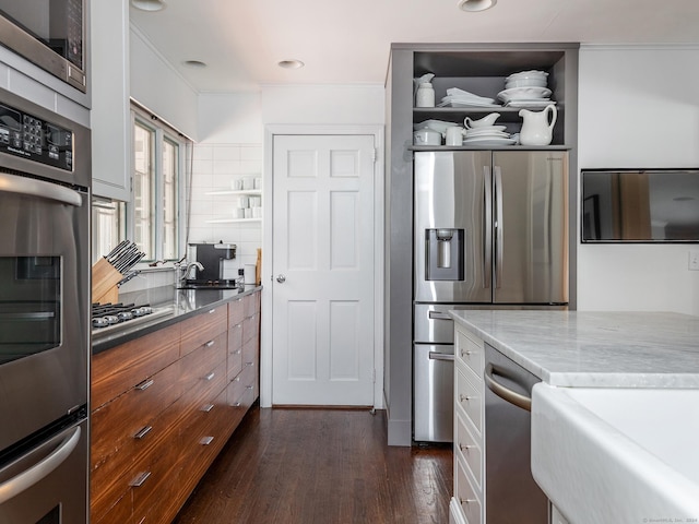 kitchen featuring dark wood-style flooring, a sink, stainless steel appliances, open shelves, and backsplash