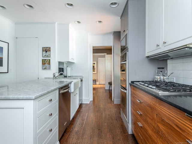 kitchen featuring stone countertops, a sink, white cabinets, appliances with stainless steel finishes, and dark wood finished floors