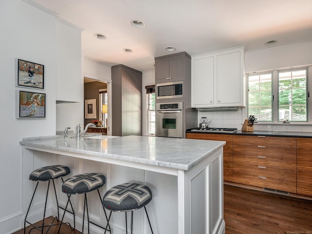 kitchen with stainless steel appliances, white cabinetry, a sink, and a peninsula