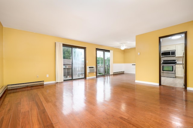 spare room with a baseboard radiator, wood finished floors, and baseboards