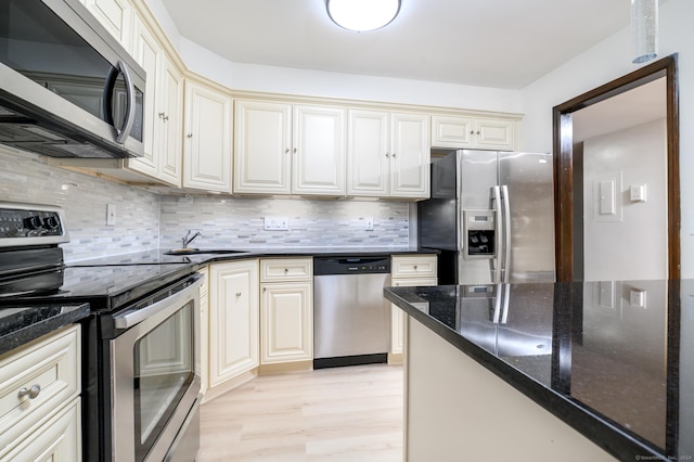 kitchen with stainless steel appliances, light wood-type flooring, decorative backsplash, and cream cabinets