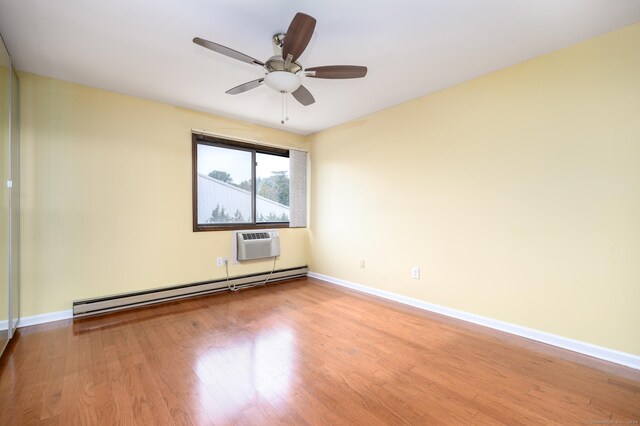 spare room featuring wood finished floors, a ceiling fan, baseboards, baseboard heating, and a wall mounted AC