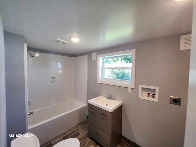 full bathroom featuring tiled shower / bath, toilet, wood-type flooring, and vanity