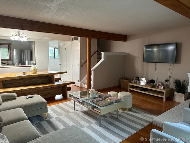 living room featuring a notable chandelier, hardwood / wood-style flooring, and a textured ceiling