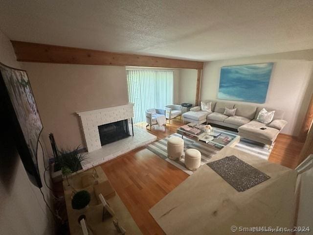 living room with wood-type flooring, a fireplace, and a textured ceiling