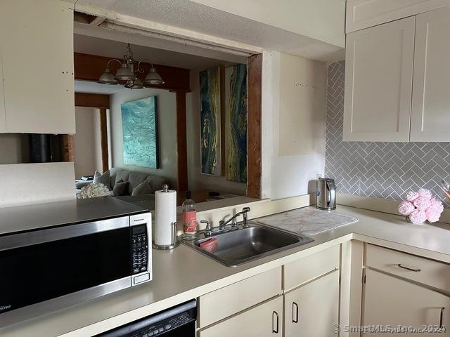 kitchen with tasteful backsplash, white cabinetry, sink, and a chandelier