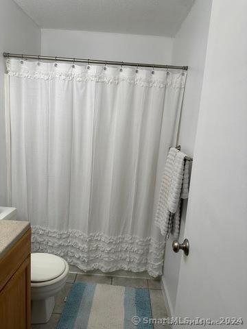 bathroom featuring tile patterned flooring, vanity, a textured ceiling, and toilet