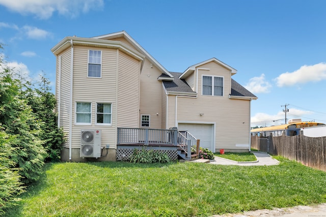 rear view of house featuring a garage, a wooden deck, and a lawn