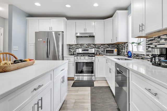 kitchen with decorative backsplash, stainless steel appliances, white cabinetry, and sink