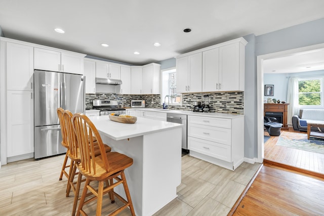 kitchen featuring white cabinets, tasteful backsplash, a center island, and appliances with stainless steel finishes