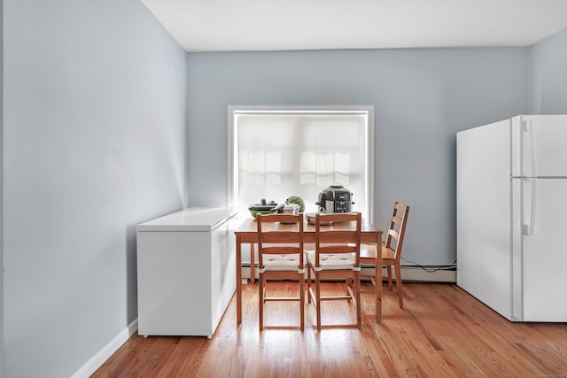 dining space featuring light wood-type flooring and a baseboard heating unit