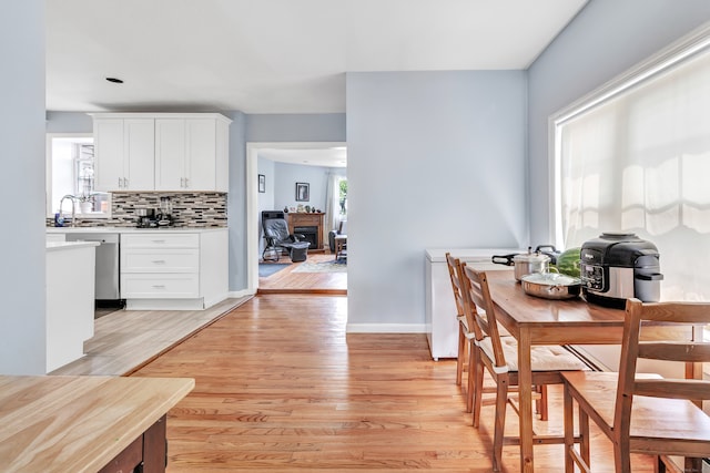 kitchen featuring white cabinetry, light wood-type flooring, tasteful backsplash, and dishwasher