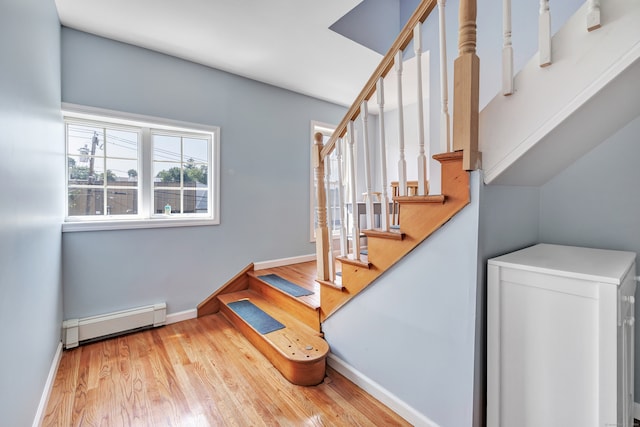 stairway with baseboard heating and light hardwood / wood-style flooring