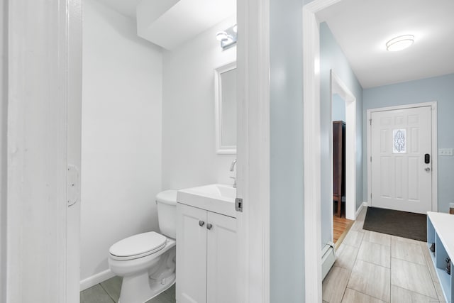 bathroom featuring tile patterned floors, vanity, baseboard heating, and toilet