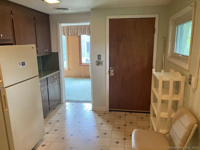 kitchen with dark brown cabinetry and white refrigerator