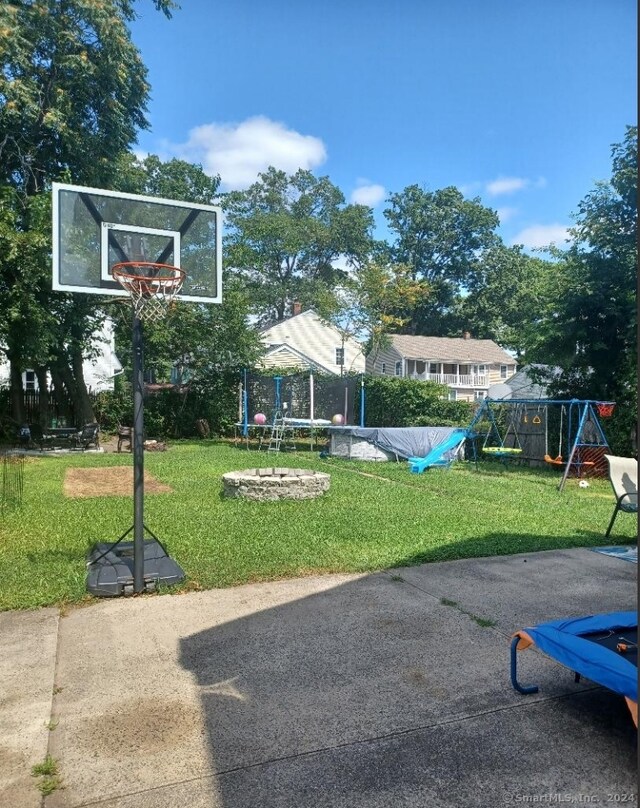 view of basketball court featuring a playground and a yard