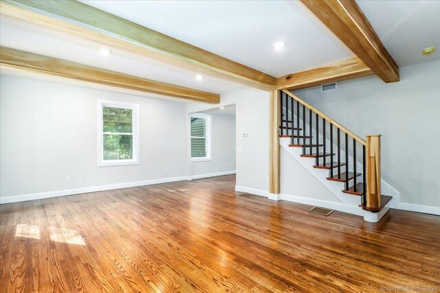 unfurnished living room featuring hardwood / wood-style floors and beamed ceiling