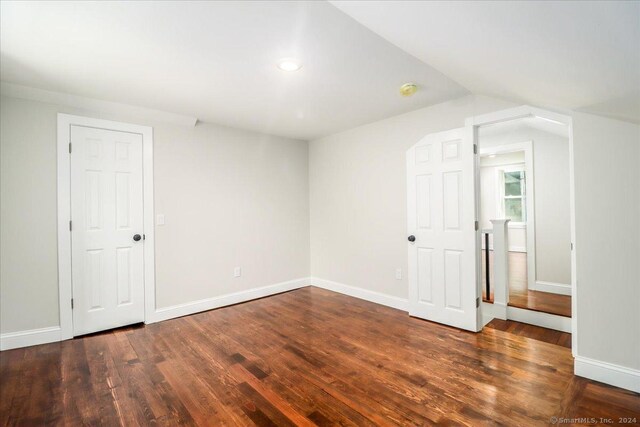 empty room with vaulted ceiling and hardwood / wood-style flooring