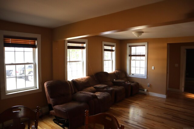 living room with a wealth of natural light, a baseboard radiator, and wood-type flooring