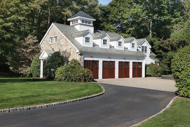 view of front of house with driveway, stone siding, a garage, and a front yard