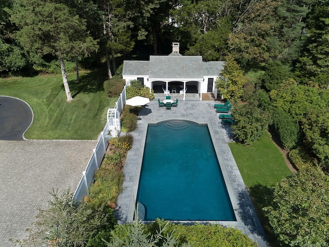 pool featuring an outbuilding, a lawn, a patio area, a fenced backyard, and a storage structure