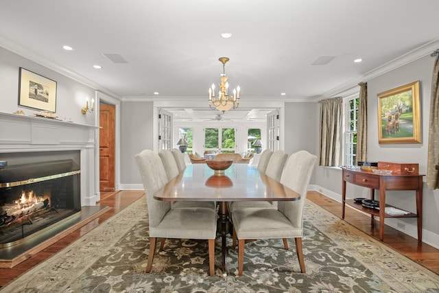 dining space with a warm lit fireplace, ornamental molding, and wood finished floors