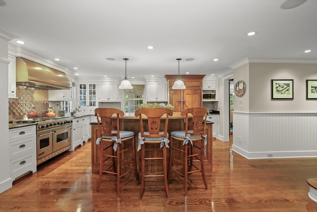 dining space featuring a wainscoted wall, ornamental molding, dark wood finished floors, and recessed lighting