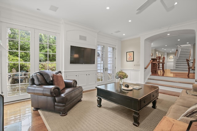 living area featuring plenty of natural light, stairs, arched walkways, and a decorative wall