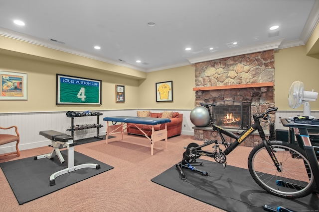 exercise area with light colored carpet, a wainscoted wall, a fireplace, visible vents, and ornamental molding