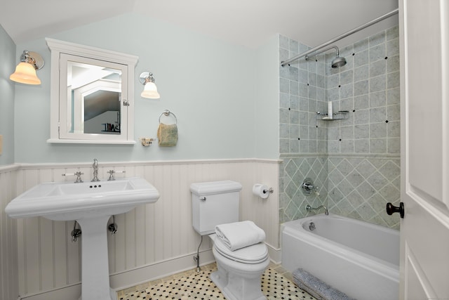 bathroom featuring lofted ceiling, toilet, wainscoting, a sink, and  shower combination