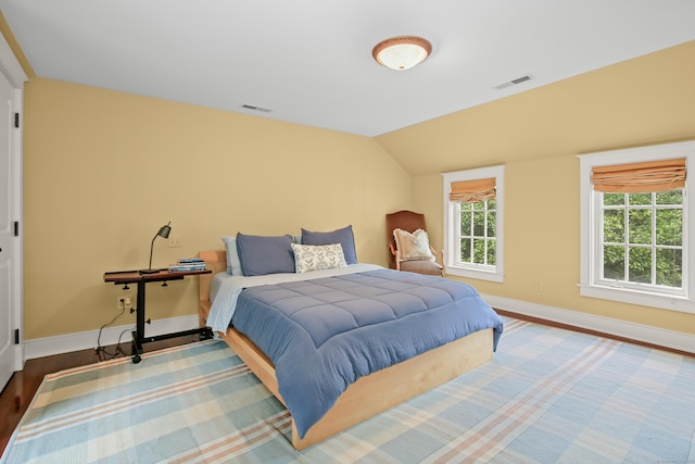 bedroom with visible vents, vaulted ceiling, baseboards, and wood finished floors