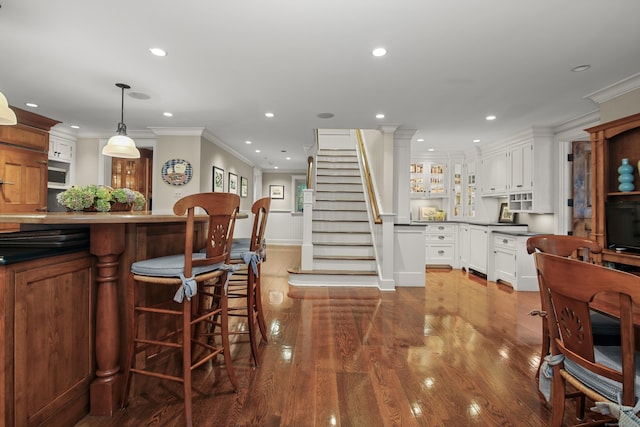 kitchen with pendant lighting, recessed lighting, glass insert cabinets, white cabinetry, and wood finished floors